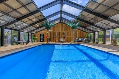 Indoor pool area with comfortable seating and palm trees