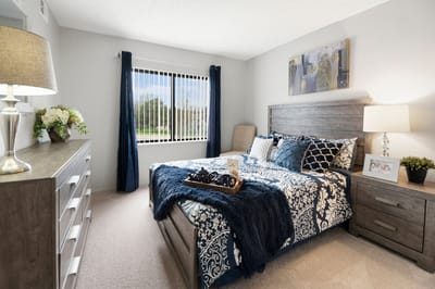 A neatly arranged bedroom with modern decor and light curtains
