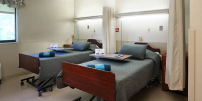 Shared resident room with two beds and bedside tables.