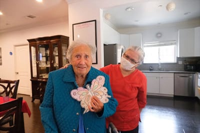 A resident holds a paper butterfly with staff assistance