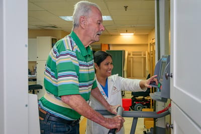 Staff assisting a resident with therapy equipment