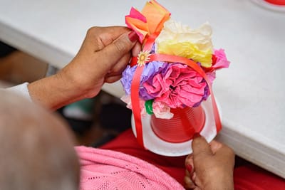 A resident crafting a floral arrangement with colorful paper.