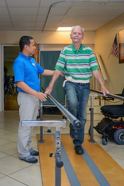 Staff assisting a resident in physical therapy