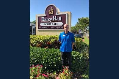Staff member in front of Darcy Hall signage