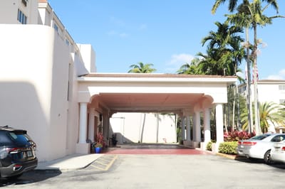 Building entrance with palm trees and parking area