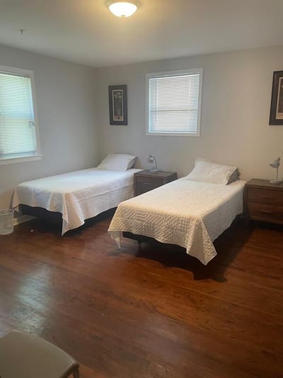 A bright bedroom with two twin beds and wooden floors