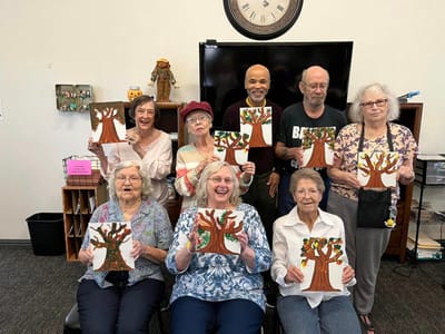 Residents participating in a creative art activity with tree paintings