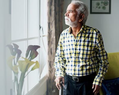 Senior man looking out a window in an interior setting