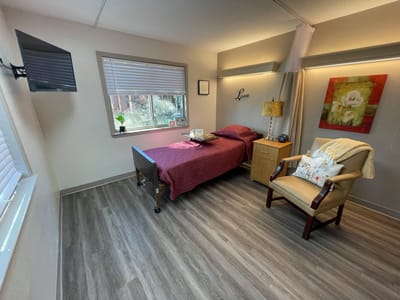 A cozy private room with bed and chair