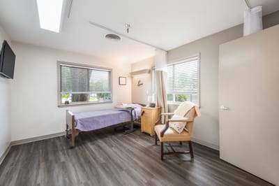 A cozy private resident room with a bed and chair