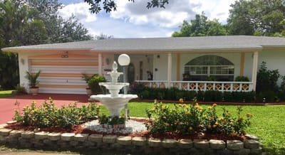 Exterior view of a residential building with garden and fountain