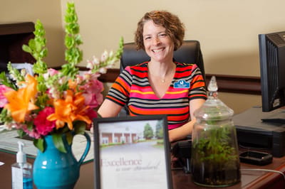 Reception area with a smiling staff member and flowers