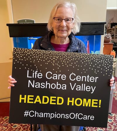 Resident celebrating with a sign at the facility