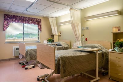 A shared room with two hospital beds and bright lighting