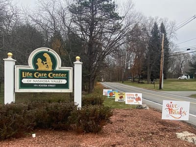 Exterior view of Life Care Center of Nashoba Valley with directional signs