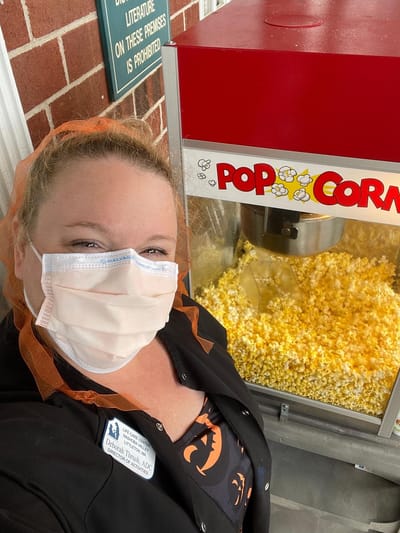 Staff member smiling near a popcorn machine