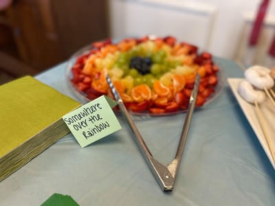 A colorful fruit platter with tongs and a note