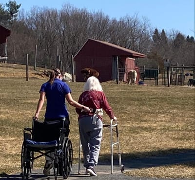 A caregiver assisting a resident outdoors.