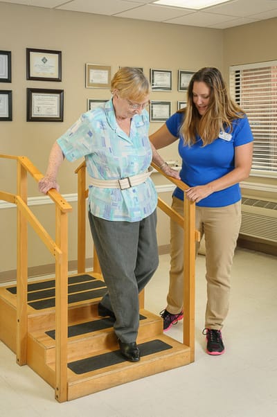 Staff assisting a resident on stairs during therapy