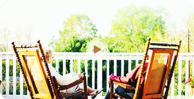 Two residents relaxing in rocking chairs on a porch