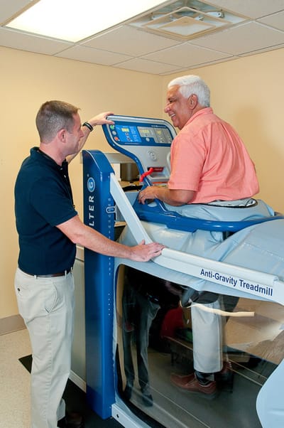 Residents using anti-gravity treadmill with staff assistance