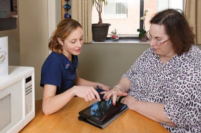 Staff member assisting resident with a tablet