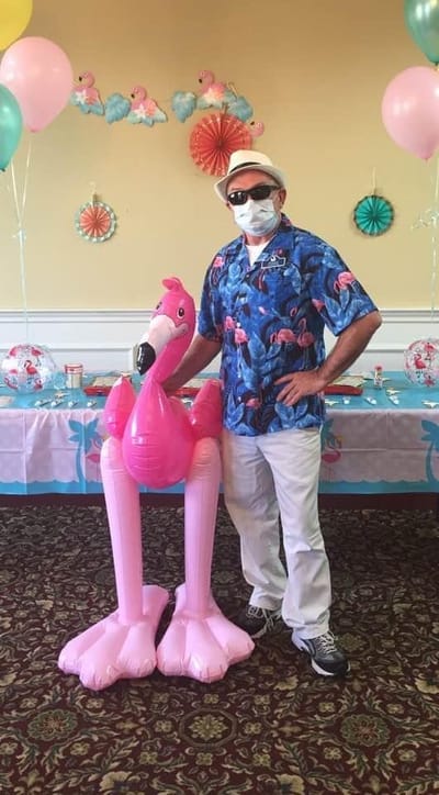 Staff member in a festive setting with inflatable flamingo