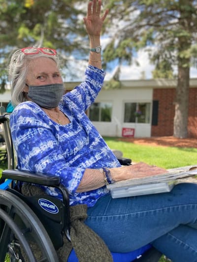 Resident in a wheelchair waving outdoors