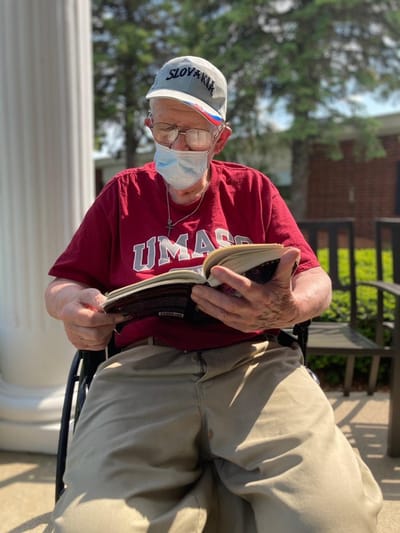 Resident reading a book outdoors in a sunny area