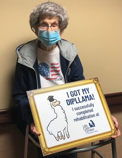 Resident celebrating rehabilitation completion with a diploma sign