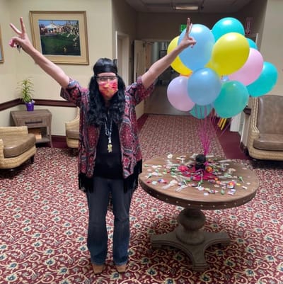 Staff member celebrating with balloons in a festive common area