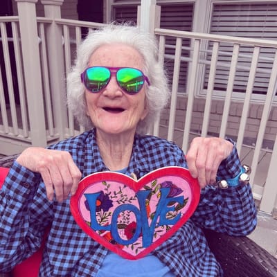 Resident holding a colorful heart sign outdoors