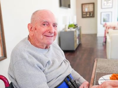 An elderly man smiling at a dining table