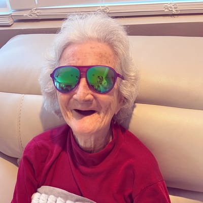 Resident smiling with vibrant sunglasses indoors