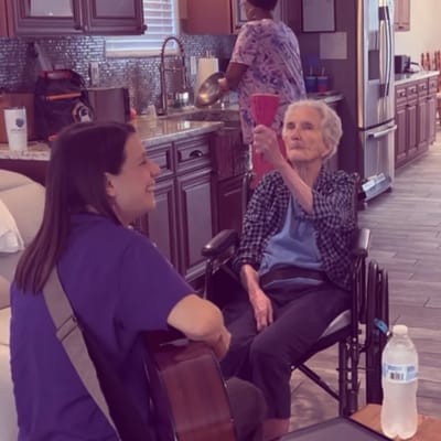 Resident enjoying music with staff member in living area