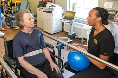 Therapist assisting a resident with a blue therapy ball