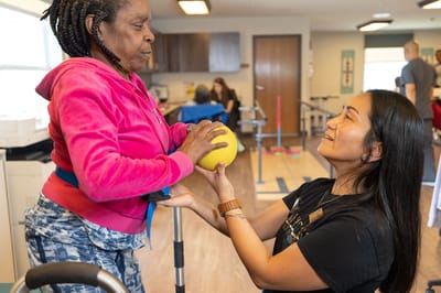 Therapist assisting resident with a yellow exercise ball