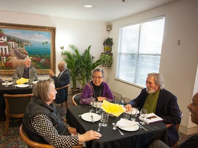 Residents enjoying a meal and conversation in a dining room