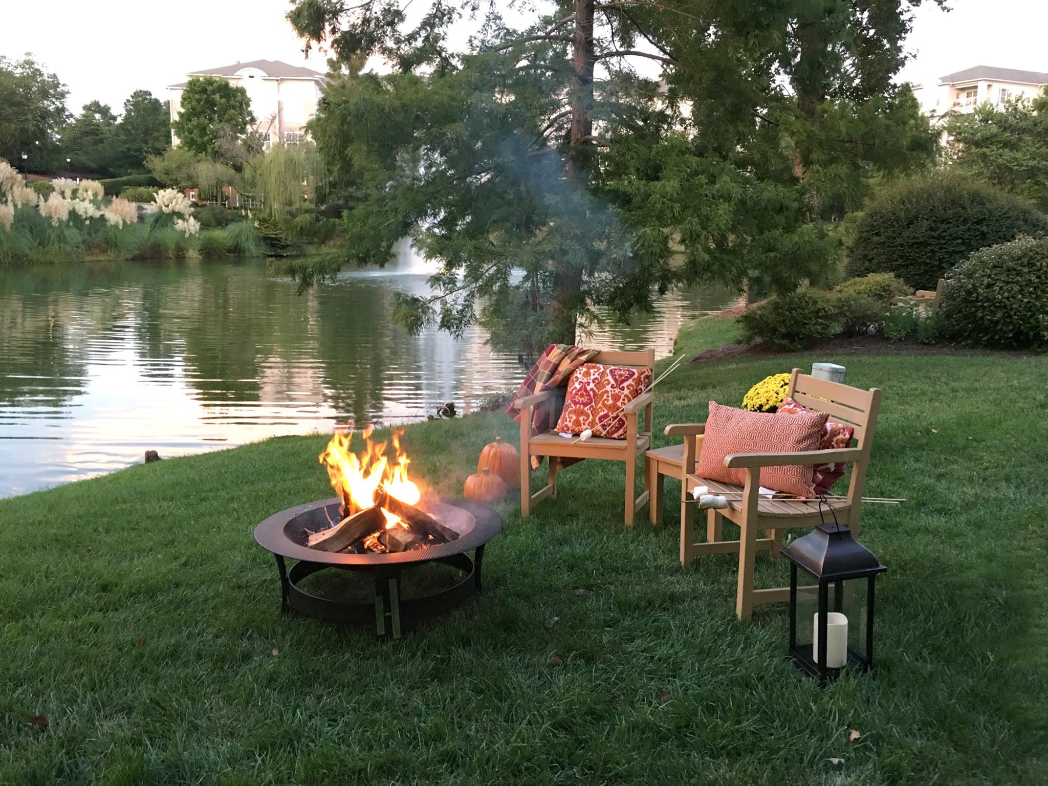 Cozy outdoor seating by a lake with fire pit.