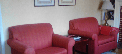 Two red armchairs with framed pictures on the wall.