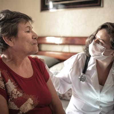 A healthcare professional attending to a senior resident.
