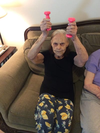 Elderly woman exercising with pink dumbbells
