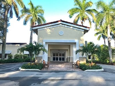 Exterior view of a nursing home entrance with palm trees