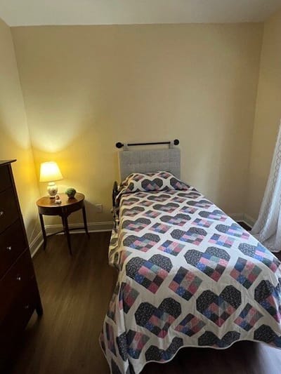 Cozy resident room with a quilted bedspread and lamp