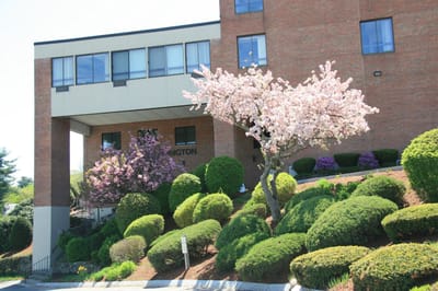 Front exterior of a senior living facility with blooming trees