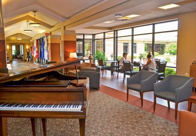 Common area with piano and seating, sunlight coming through windows