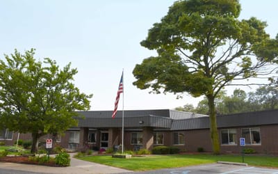 Exterior view of the facility with trees and flag.