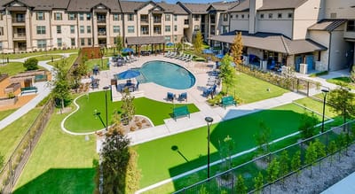 Aerial view of a large assisted living facility with a pool and gardens