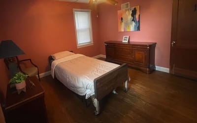 A simple private resident room with a bed and dresser