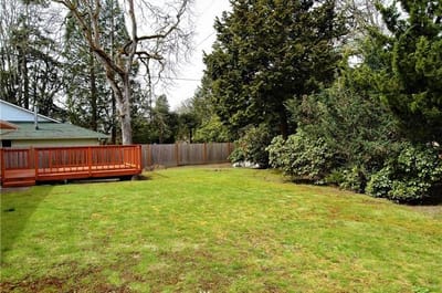 Spacious green backyard with deck and trees